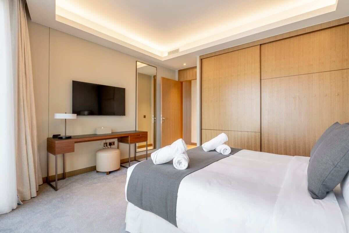 A hotel room with a bed, a desk, a chair, a television, and a mirror.
