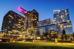 Eine moderne Stadtlandschaft mit Hochhäusern, einem öffentlichen Platz und einer markanten, kreisförmigen Lichtinstallation.