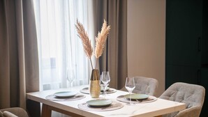 Een eettafel gedekt met borden, glazen en een vaas met pampa gras.
