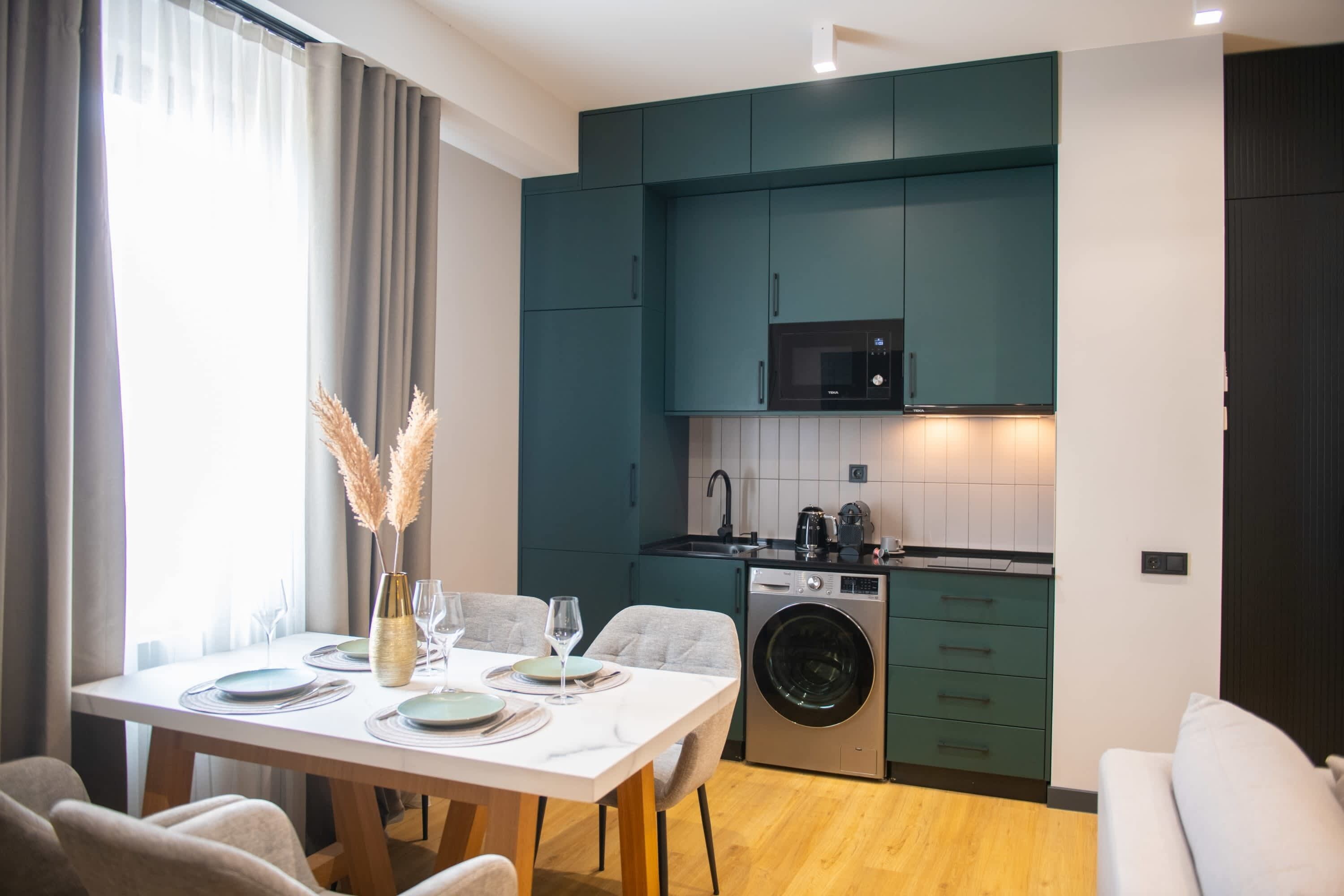 A compact kitchen with a microwave, sink, and washing machine.
