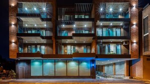 Een modern meerlaags gebouw met balkons en grote ramen, met een bakstenen gevel en buitenverlichting.