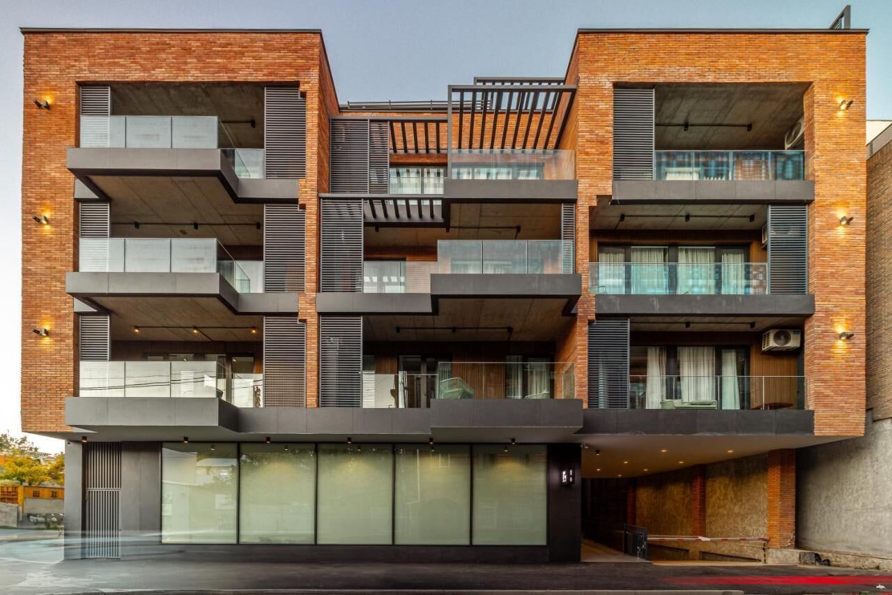 Un edificio moderno de varios pisos con balcones, ventanas amplias y fachada de ladrillo.