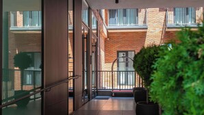 A modern building with a glass entrance, metal railings, and a potted plant. - Studio Balcony Suite with Kitchen (T'bilisi)