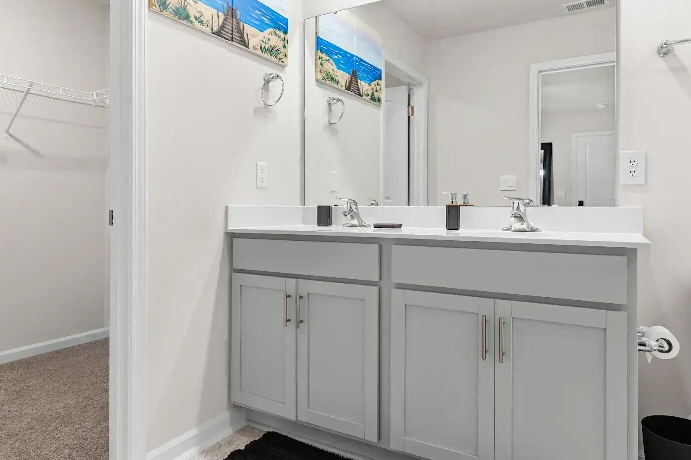 Un baño moderno con tocador doble, un espejo grande y un perchero para toallas.