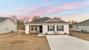 A single-story house with a front porch, a small yard, and a clear sky.