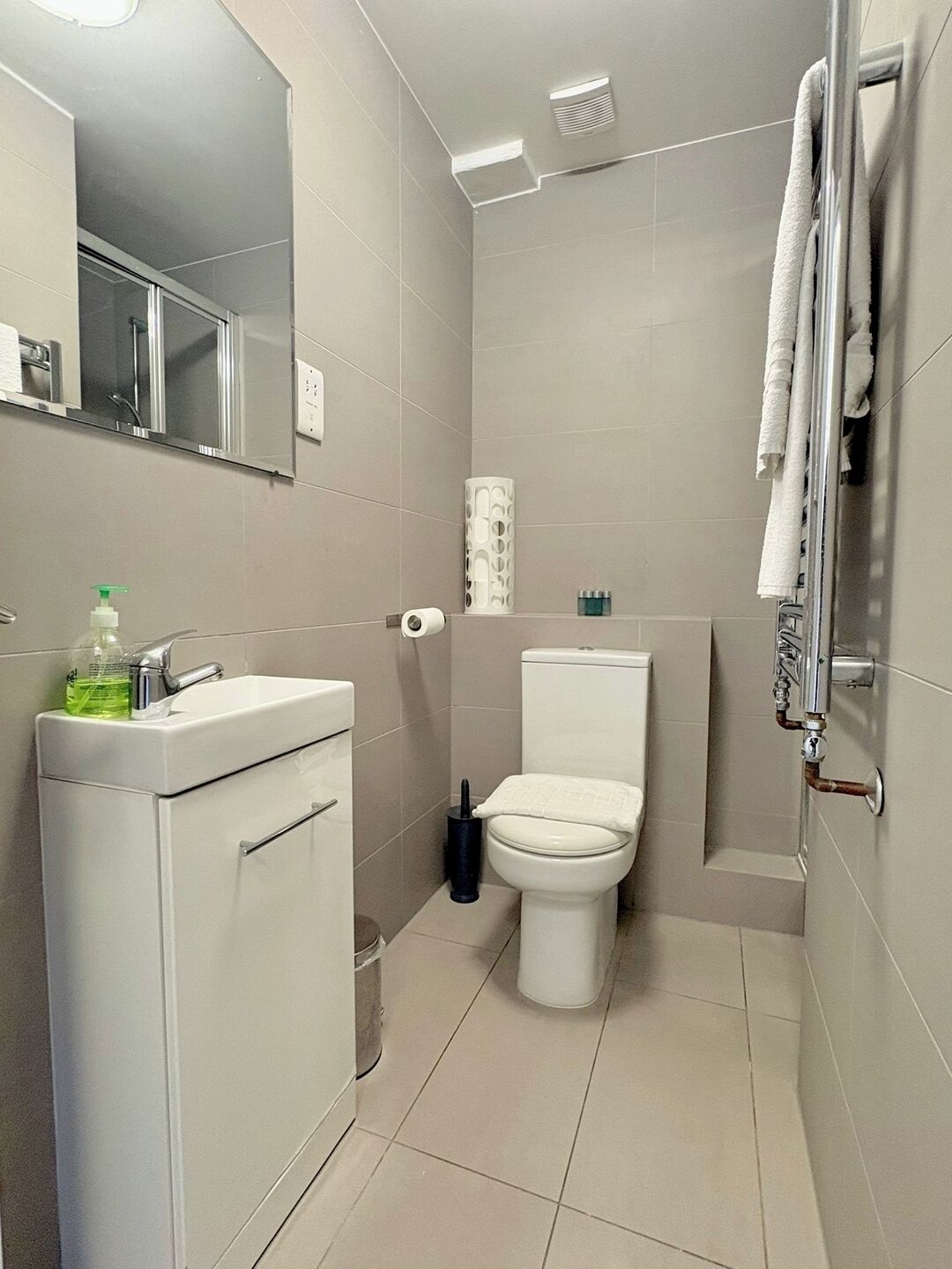 Ein Badezimmer mit Toilette, Waschbecken, Spiegel und Dusche.