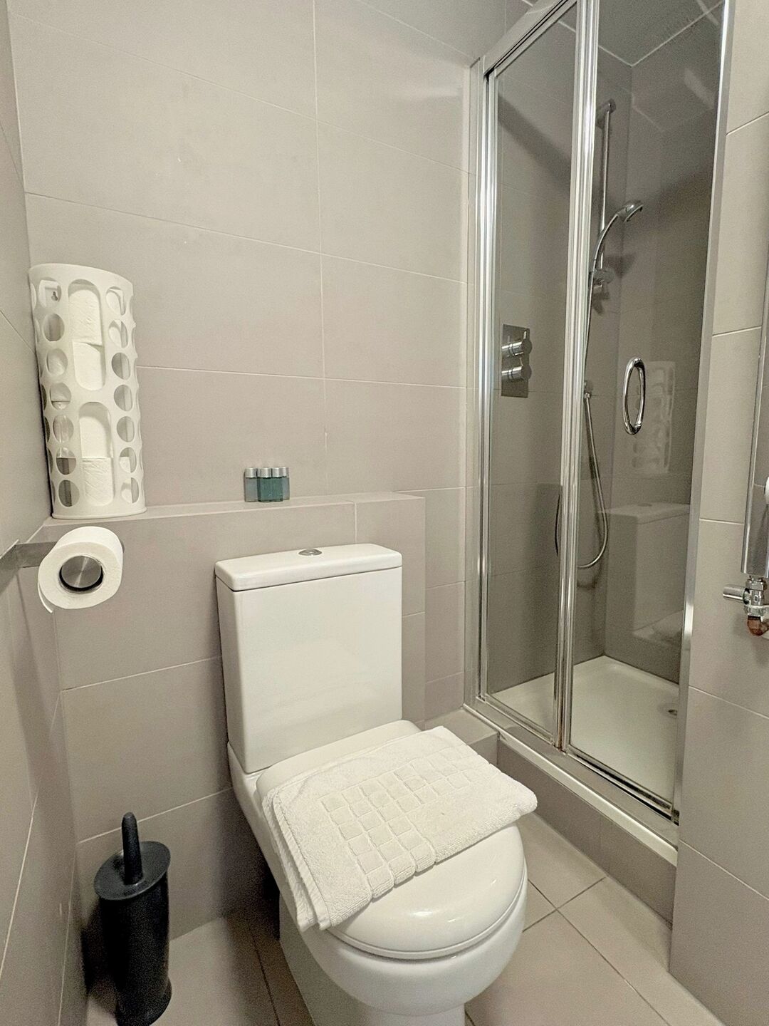 Une salle de bain équipée de toilettes, d’une douche et d’un porte-rouleau de papier toilette.