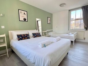 Ein Hotelzimmer mit zwei Betten, einem Vorhangfenster, einem Heizkörper und einem Spiegel.