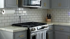 A kitchen with grey cabinets, a stainless steel range hood, a gas stove, and a microwave. - Relaxing Space for Families & Friends — Sleeps 10 + Pet-Friendly (Grandview)