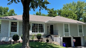 A two-story house with a brick facade, large windows, a front porch, and a garage. - Relaxing Space for Families & Friends — Sleeps 10 + Pet-Friendly (Grandview)