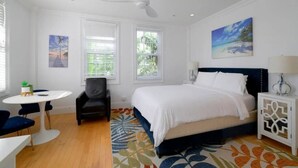 Une chambre à coucher avec un lit, un bureau, une chaise et un ventilateur de plafond.