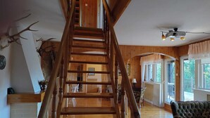 A wooden staircase with a view to a dining area and a large window. - Half of a Holiday Home, Large Garden, Terrace (gmina Stężyca)