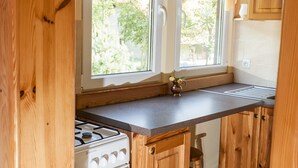 A kitchen with wooden cabinets, a stove, and a window with a view of greenery. - Half of a Holiday Home, Large Garden, Terrace (gmina Stężyca)