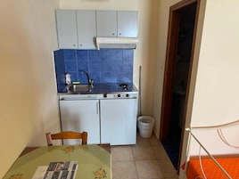A compact kitchen with a gas stove, white cabinets, and a blue backsplash.