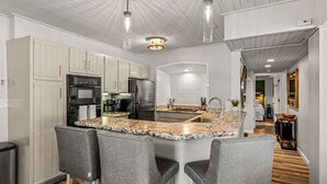 Eine moderne Küche mit Granit-Arbeitsplatten, Edelstahlgeräten und einer zentralen Kochinsel mit Barhocker.