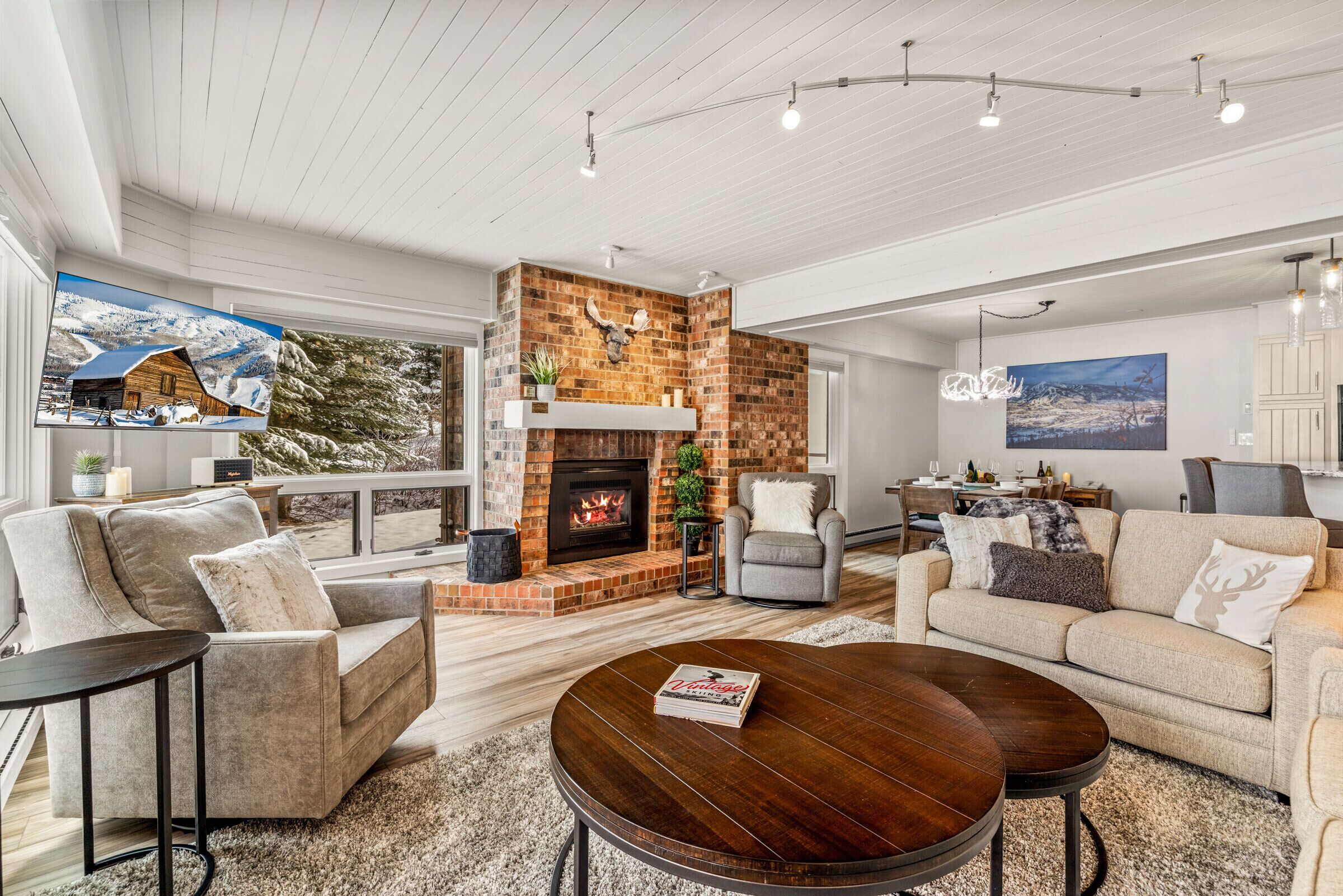 A modern living room with a fireplace, comfortable seating, and a large TV.