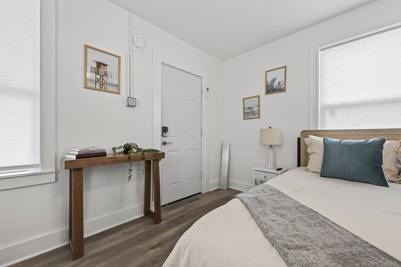 A bedroom with a bed, bedside table, lamp, and framed pictures on the wall.