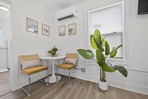 A small room with a round table, two chairs, a potted plant, and framed pictures on the wall. - Cozy Cottage Studio in Pensacola (Pensacola)