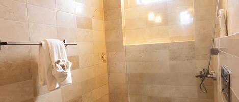 A modern bathroom with a glass-enclosed shower, a toilet, and a towel rack.