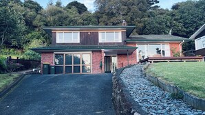 A two-story house with a brick facade, large windows, and a green roof. - Holiday Home In Red Hill Papakura Auckland With Beautiful Views (Papakura)