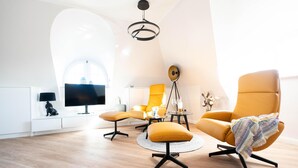 Un salon moderne avec un plafond haut, une table basse ronde et deux fauteuils.