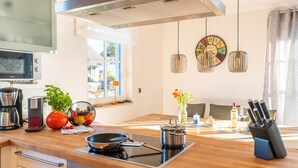 Une cuisine moderne équipée d’une cuisinière intégrée, d’une machine à café et d’un panier à fruits.