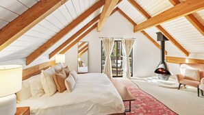 A bedroom with a large bed, a wooden ceiling, a fireplace, and a view of the outdoors. - Close to Ski Slopes & Trails ~ Zoo ~ Hot Tub (Big Bear)