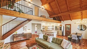 A spacious living area with a wooden staircase, a kitchen, and a dining area. - Close to Ski Slopes & Trails ~ Zoo ~ Hot Tub (Big Bear)