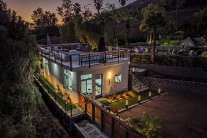 Una casa moderna con un balcone, un piccolo giardino e una zona piscina.