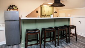 Una cocina con isla integrada, refrigerador y taburetes de bar.