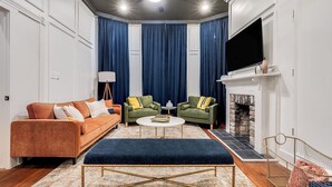 Un salon comprenant un canapé, deux fauteuils, une table basse, une cheminée et un téléviseur.
