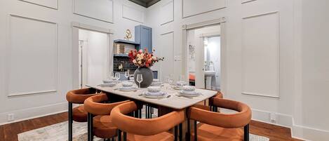 A dining area with a rectangular table set for six, surrounded by six orange chairs.