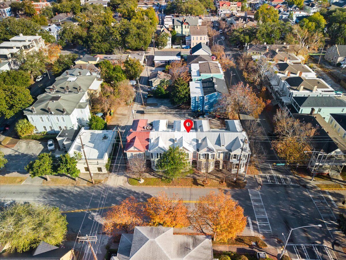 An aerial view of a residential area with houses, streets, and a prominent building with a red marker on its roof.