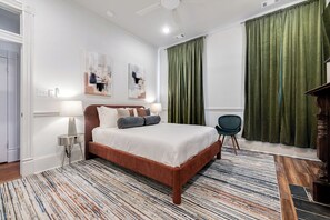 Une chambre à coucher avec un lit, une chaise, une lampe et des œuvres d’art accrochées au mur.