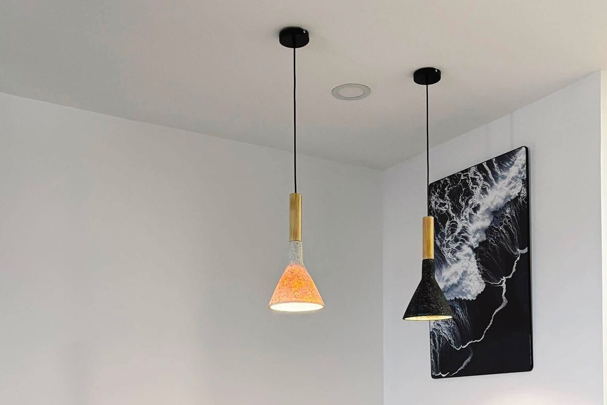 A dining area with a wooden table and four chairs, two pendant lights, and a wall-mounted artwork.