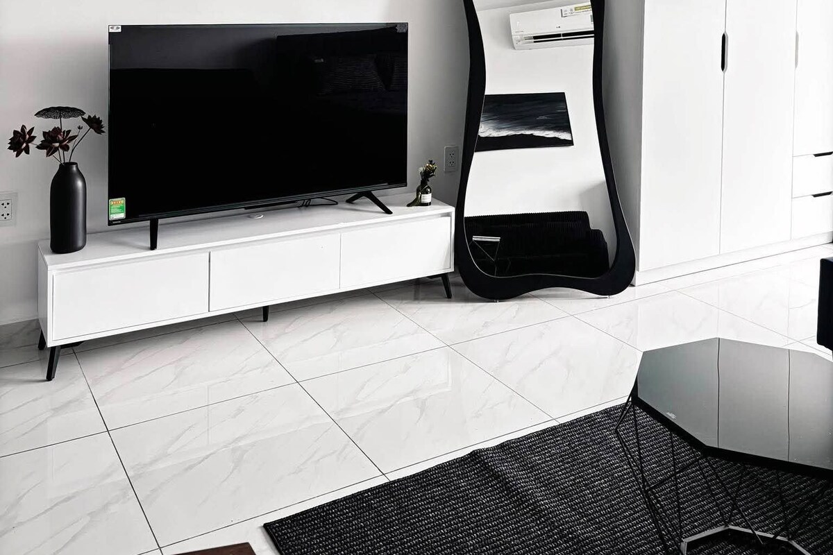 A modern living room with a flat-screen TV, a large mirror, and a white cabinet.