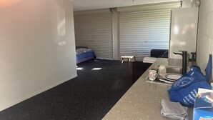 A hotel room with a bed, a small table, a sink, and a mirror. - Far North holiday base with panoramic coastline outlook and comfy sleepout (Kaitaia)