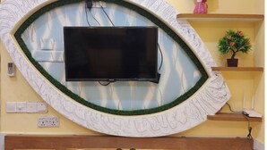 A wall-mounted television with a decorative border, electrical outlets, and a small potted plant.