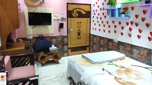 A hotel room with a bed, a desk, a chair, a TV mounted on the wall, and a door with a decorative design.