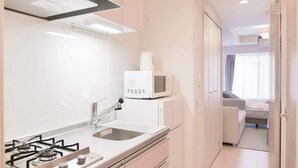 Eine kleine Küche mit Gaskochfeld, Spüle und Mikrowelle.