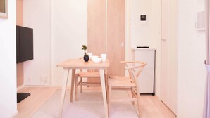 Een kleine kamer met een houten tafel, een stoel, een kleine bloempot en een witte kast.
