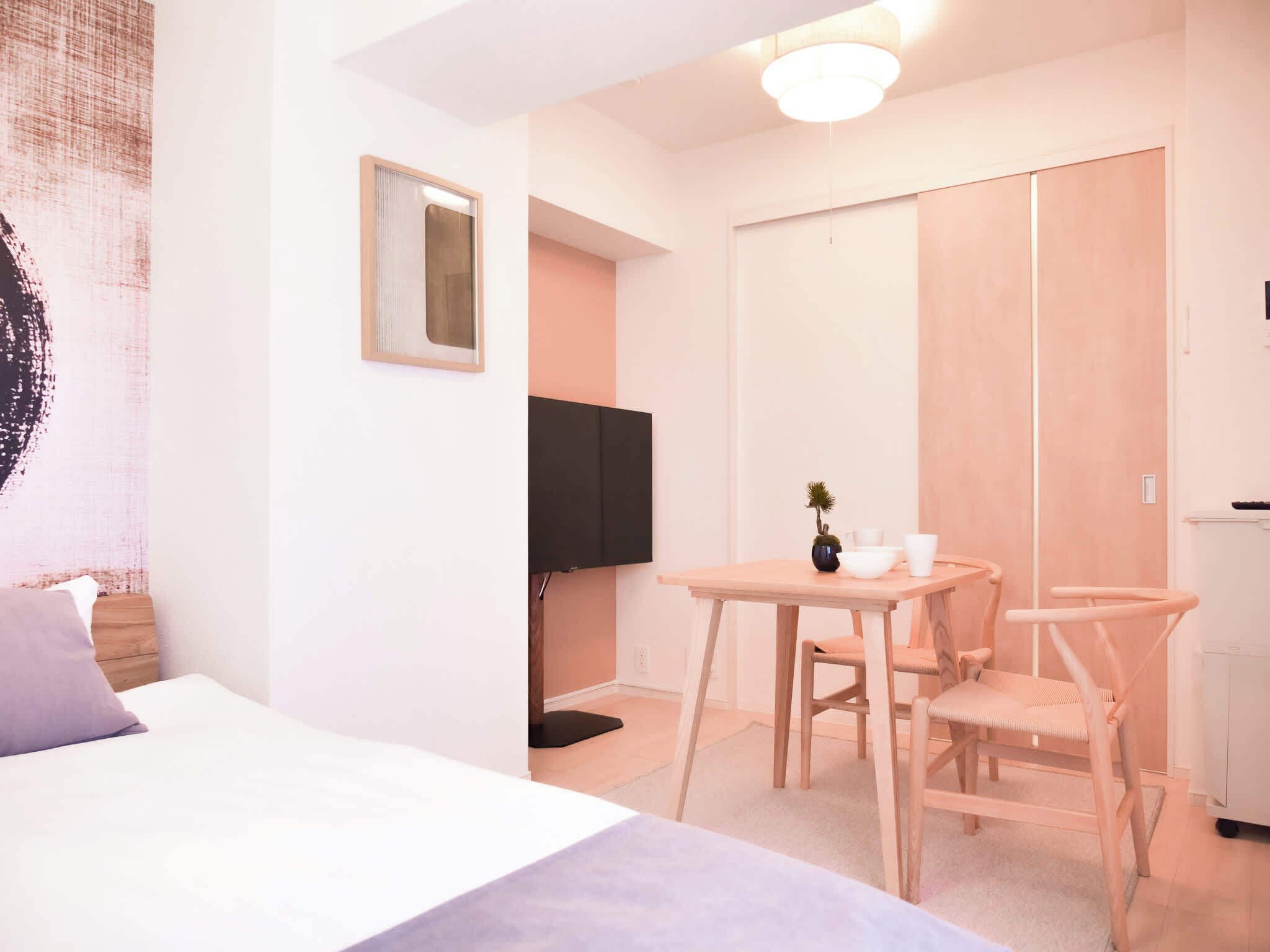 Ein Schlafzimmer mit einem Bett, einem Nachttisch, einem kleinen Tisch mit Stühlen, einem Fernseher und einem Kleiderschrank.