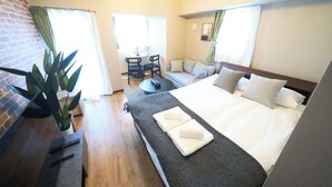 Camera d'albergo con un letto, una scrivania, una sedia e una pianta in vaso.