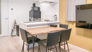 A modern kitchen with a built-in microwave, a sink, and a stove. There is a dining table with four chairs. - Triphome Asakusa Alpha 3min to Sensoji Temple (Taito City)