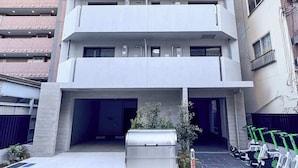 A multi-story building with a central entrance and a parking area with electric scooters. - Triphome Asakusa Alpha 3min to Sensoji Temple (Taito City)