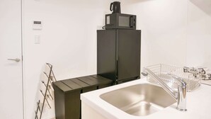 A compact kitchen with a black refrigerator, a stainless steel sink, and a kettle on top. - Triphome Asakusa Alpha 3min to Sensoji Temple (Taito City)