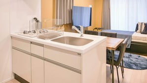 A compact kitchen with a sink, a small dining area, and a sofa. - Triphome Asakusa Alpha 3min to Sensoji Temple (Taito City)