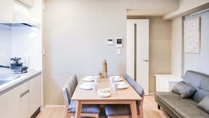 A compact living space with a kitchenette, a dining table set for four, and a sofa. - Triphome Asakusa Alpha 2 Bedrooms (Taito City)