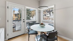 Ein stilvoller Essbereich mit einem runden Tisch, Stühlen und Blick auf eine verschneite Landschaft durch große Fenster.