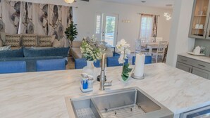 Una cocina moderna con encimera de mármol, pileta de acero inoxidable y ventilador de techo.